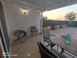 eine Terrasse mit einem Tisch und Stühlen und Blick auf den Sonnenuntergang in der Unterkunft Andrew's sunset view apartment in Loutraki