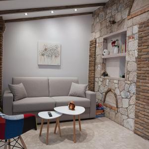 a living room with a couch and a stone wall at Boutique Eptalofos 15min from airoport and sea in Kouvarás