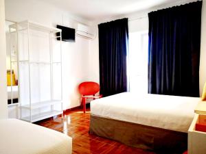 1 Schlafzimmer mit 2 Betten und einem roten Stuhl in der Unterkunft Bulldog Inn - Duna Parque Resorts & Hotels in Vila Nova de Milfontes