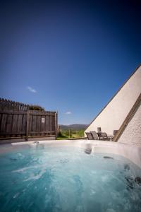 een hot tub met blauw water in een achtertuin bij Kirkstone Lodge in Insh