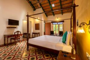 a bedroom with a bed and a desk in a room at amã Stays & Trails, Rare Earth Estate in Madikeri