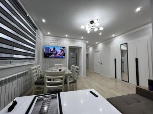 a dining room with a table and a tv on the wall at Entire Apartment in Central Nukus in Nukus