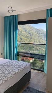 a bedroom with a bed and a large window at Villa Camgüzeli Kivili Konak’ta! in Fethiye