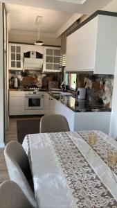 uma cozinha com uma mesa e armários brancos em Villa Camgüzeli Kivili Konak’ta! em Fethiye