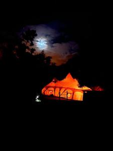 une tente éclairée la nuit avec la lune dans l'établissement Arambha Ecovillage Permaculture Farm, à Tábua