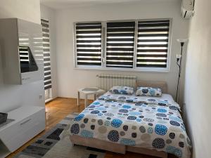 ein Schlafzimmer mit einem Bett und zwei Fenstern in der Unterkunft MKA suite in Kragujevac