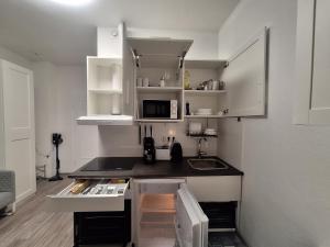 eine kleine Küche mit weißen Schränken und einem Waschbecken in der Unterkunft Apartment 16 - 2R1 in Essen