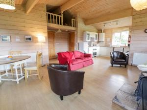 uma sala de estar com um sofá vermelho e uma mesa em Curlew Lodge em Dumfries