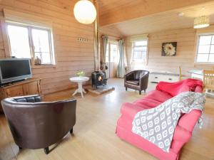 a living room with a red couch and a tv at Curlew Lodge in Dumfries