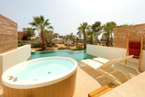 een badkamer met een bad en een stoel bij TRS Ibiza Hotel -Adults Only in San Antonio