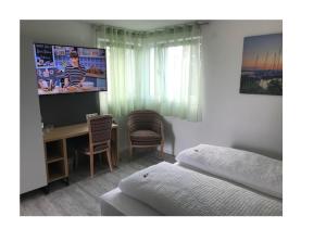 - une chambre avec un lit, un bureau et une télévision dans l'établissement Bodensee Sunshine Zimmer & Apts., à Uhldingen-Mühlhofen