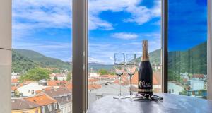 una botella de vino y dos copas en una mesa frente a una ventana en PLAZA Premium Heidelberg, en Heidelberg