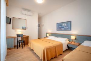 a hotel room with two beds and a desk at Hotel Parigi in Caorle