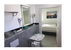 uma casa de banho com um lavatório e um espelho em Bodensee Sunshine Zimmer & Apts. em Uhldingen-Mühlhofen