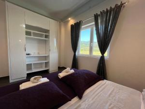 sypialnia z fioletowym łóżkiem i ręcznikami w obiekcie Adriatik Guesthouse w mieście Përmet