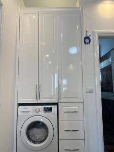 a washing machine in a kitchen with white cabinets at Adriatik Guesthouse in Përmet