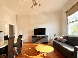 a living room with a couch and a table and a tv at Victorian Terrace in the heart of it all! in Melbourne