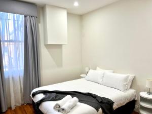 a bedroom with a bed with white pillows and a window at Victorian Terrace in the heart of it all! in Melbourne