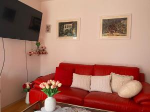 a red couch in a living room with a vase of flowers at Cozy Room + shared kitchen + shared bathroom + free parking in Hvar