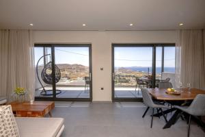a living room with a table and chairs and sliding glass doors at Pearl Suites and Villa Tinos in Tinos Town