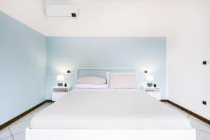 una camera bianca con un grande letto bianco con due lampade di Villa Porpora Luxury Design a Modena