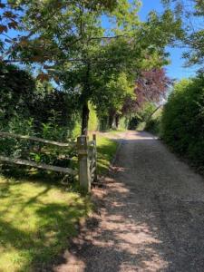 a dirt road with a fence and trees on it at Mulberry Barn located in the South Downs National Park in Ditchling