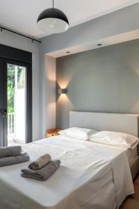a bedroom with a white bed with two towels on it at Hippocrates bound by BiNoBi! in Thessaloniki