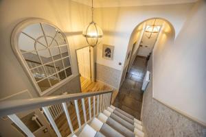 korytarz ze schodami z lustrem i żyrandolem w obiekcie Porte House - Holiday At Home w mieście Richmond