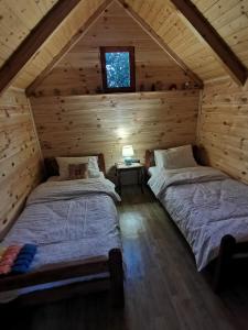 two beds in a log cabin with a window at Bungalov Živković in Mojkovac