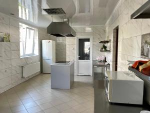 eine weiße Küche mit einem Kühlschrank und einer Spüle in der Unterkunft Вілла MILARO in Schidnyzja