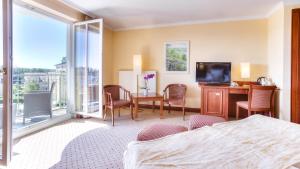 ein Hotelzimmer mit einem Bett, einem Schreibtisch und einem TV in der Unterkunft Hotel zur Post - ein Rovell Hotel in Bansin