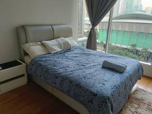 a bedroom with a bed with a blue comforter and a window at Lovely 3 Rooms with KLCC View, Pavilion & Netflix in Kuala Lumpur