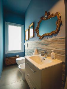 een badkamer met een wastafel, een toilet en een spiegel bij Casa di Marina, tra Etna e mare. in Gravina di Catania