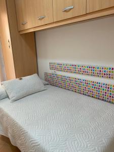 a bedroom with a white bed with a colorful headboard at Apartamentos Alcañiz, Alicia in Alcañiz