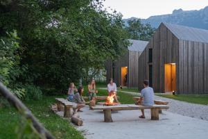 a group of people sitting around a fire on benches at Cabino - Fresh Air Resort in Bovec