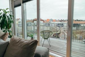 Large Apartments - Great for Groups - with Balcony or Terrace في فيينا: غرفة معيشة مع أريكة وشرفة مع نوافذ