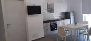 cocina con armarios blancos, mesa y sillas en Tenuta Nonna Peppa Luxury apartment, en Palinuro