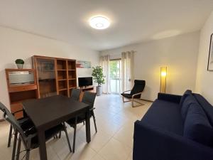 コスタ・ダ・カパリカにあるCaparica's Beach Apartment by Trip2Portugalのリビングルーム(青いソファ、テーブル付)
