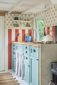 una cocina con armarios azules y una ventana en Fleur de Grog - Shepherds Hut, en Bodmin