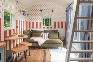 a living room with a green couch and red and white stripes at Fleur de Grog - Shepherds Hut in Bodmin