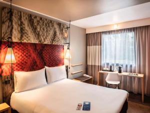 een hotelkamer met een groot bed en een bureau bij Hotel Ibis Krakow Centrum in Krakau