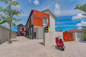 a red scooter parked in front of a house at Urbanview Hotel Griya Menteng Palangkaraya by RedDoorz in Tumbangrungan