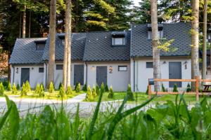 a white building with grey doors and trees at Boro Green Holiday Village in Borovets