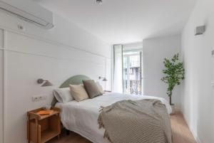 a white bedroom with a bed and a window at B48 Abando in Bilbao