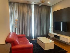 sala de estar con sofá rojo y TV de pantalla plana en 3 Guests,200m to KLCC & Pavilion Mall with Netflix en Kuala Lumpur