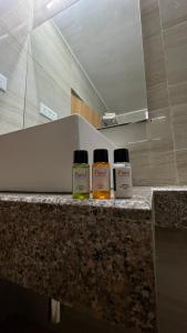 tres botellas de aceites esenciales sentadas en un mostrador en un baño en Hotel The Bundela - Khajuraho, Madhya Pradesh en Khajurāho