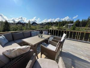 a patio with a couch and a table on a deck at Tisleibu - cabin at Golfjellet in Tisleidalen