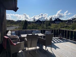 a patio with a couch and chairs on a deck at Tisleibu - cabin at Golfjellet in Tisleidalen