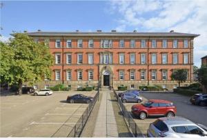 a large red brick building with cars parked in a parking lot at County House Escape - courtyard & free parking in York