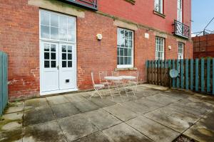 a patio with a table and chairs in front of a brick building at County House Escape - courtyard & free parking in York